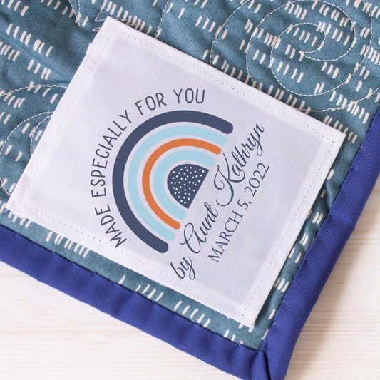 Custom baby quilt label with a rainbow in shades of blue - Jammin Threads
