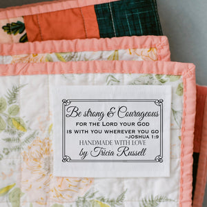 Personalized quilt label with Bible verse Joshua 1:9 reading “Be strong and courageous for the Lord your God is with you wherever you go” sewn onto a quilt.